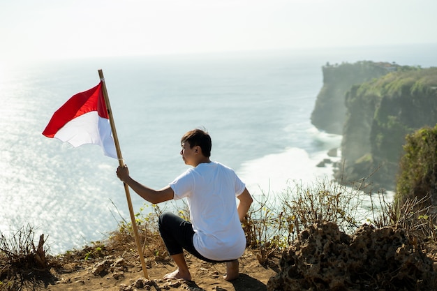 Photo homme asiatique avec drapeau indonésien de l'indonésie au sommet de la montagne