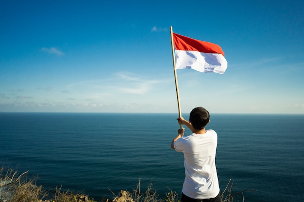 Homme asiatique avec drapeau indonésien de l'Indonésie au sommet de la montagne