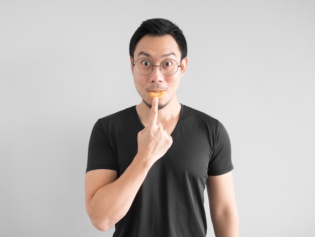 Homme asiatique drôle montrant comment manger des biscuits d&#39;une manière heureuse.