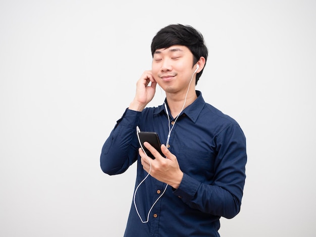 Homme asiatique écoutant de la musique avec des écouteurs et tenant son téléphone portable heureux et se détendre l'émotion