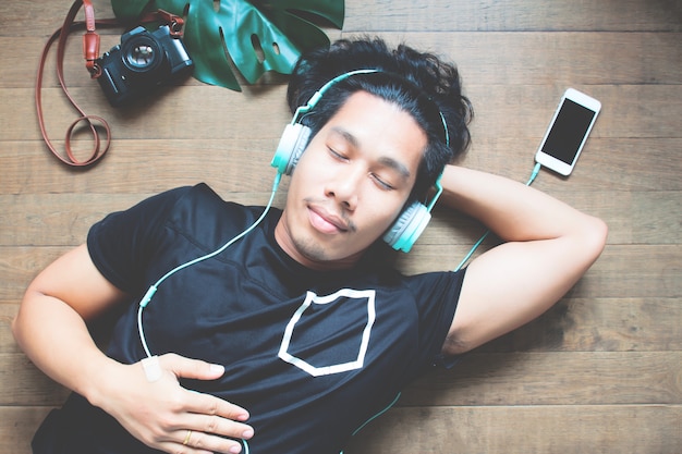 Homme asiatique écoute la musique par smartphone fixant avec caméra