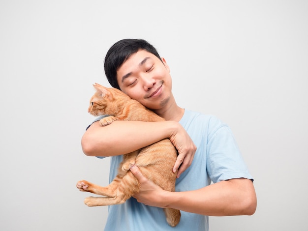 Un homme asiatique embrasse son chat de couleur orange dans la main, se sentant heureux