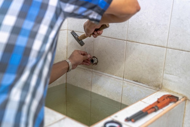 Un homme asiatique essaie de réparer et de réparer une douche à tuyau dans les anciennes toilettes