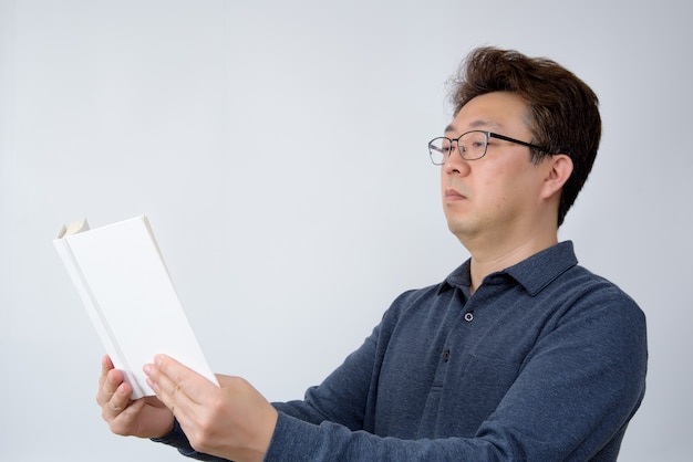 Homme asiatique essayant de lire quelque chose dans son livre. mauvaise vue, presbytie, myopie.