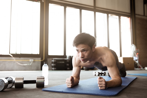 Homme asiatique exerçant dans la salle de sport