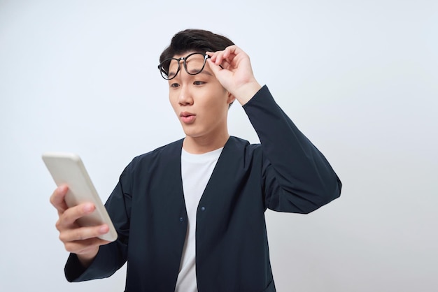 Homme asiatique heureux de voir quoi dans le smartphone sur fond blanc isolé