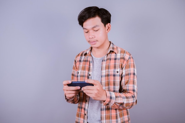 Homme asiatique jouant à des jeux sur tablette smart Phone contre sur fond gris