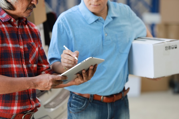 Photo homme asiatique livraison bonne boîte au client en usine et signature sur tablette sourire et bon service, concept de magasinage logistique en ligne