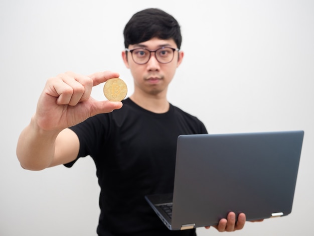 Homme asiatique avec des lunettes tenant bitcoin et ordinateur portable sur fond blanc