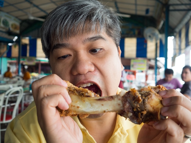 Homme asiatique mangeant de l&#39;os de porc Après avoir mangé la jambe du jarret de porc grillé et croustillant.