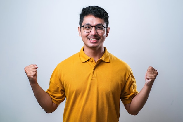 Homme asiatique montrant une expression heureuse et excitée avec le poing fermé sur fond blanc