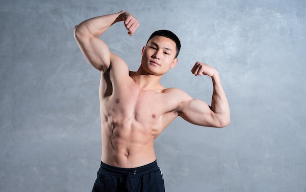 Homme asiatique musclé posant sur fond gris