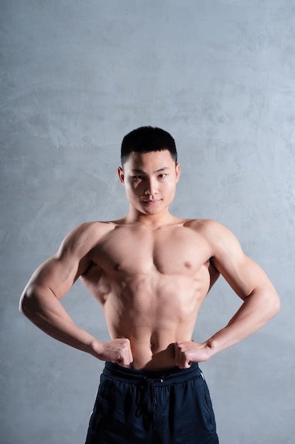 Homme asiatique musclé posant sur fond gris