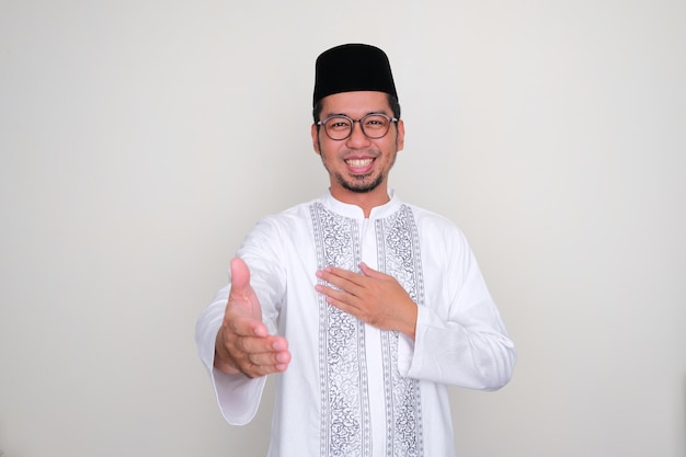 Homme asiatique musulman souriant amicalement tout en offrant une poignée de main