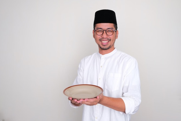 Homme asiatique musulman souriant heureux tout en tenant une assiette vide