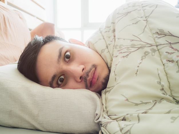 Photo l'homme asiatique ne peut pas dormir dans la lumière du matin avec des yeux noirs sans sommeil.