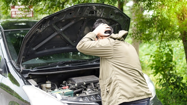 Un homme asiatique a ouvert le capot de la voiture alors qu'il était confus