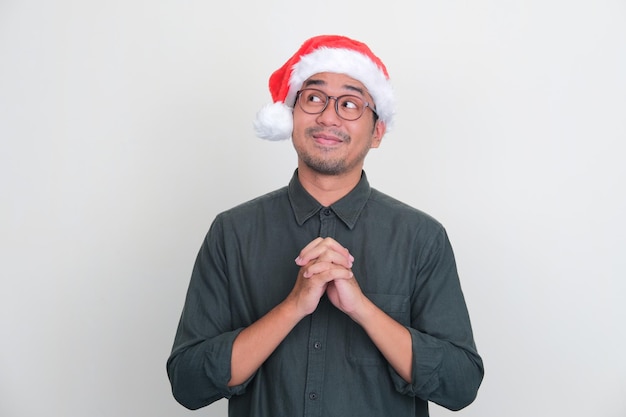 Photo homme asiatique portant un chapeau de noël souriant tout en regardant sur le côté droit