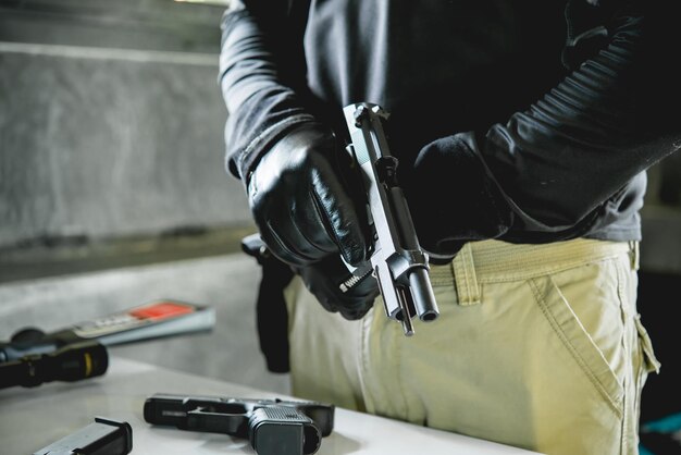 Homme asiatique portant des gants en cuir noir avec un pistolet à chargement manuel des balles au pistolet