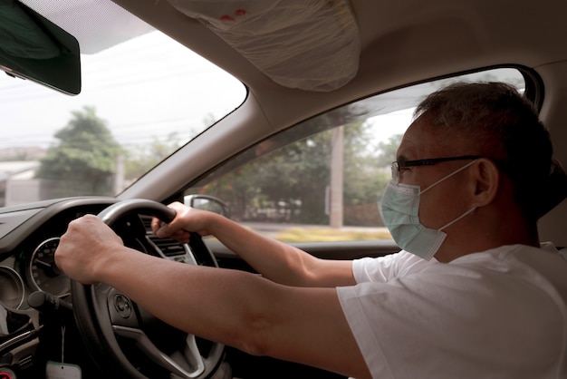 Homme asiatique portant un masque médical en conduisant