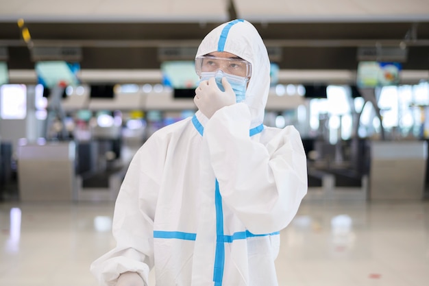 Un homme asiatique porte un costume ppe à l'aéroport international, voyage de sécurité, protection covid-19, concept de distance sociale