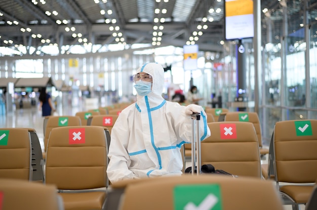 Un homme asiatique porte un costume ppe à l'aéroport international, voyage de sécurité, protection covid-19, concept de distance sociale.