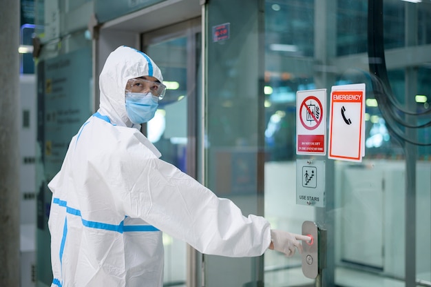 Un homme asiatique porte un costume ppe dans l'ascenseur de l'aéroport, voyage de sécurité, protection covid-19, concept de distance sociale