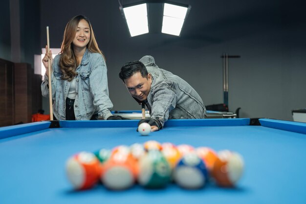 Homme asiatique poussant la boule blanche pour commencer la partie de billard au studio de billard