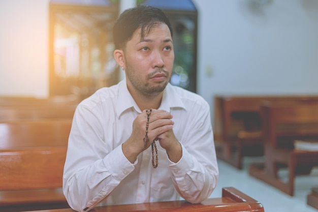 Homme asiatique priant dans une église chrétienne.