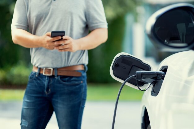 Un homme asiatique progressiste recharge sa voiture EV à la station de charge à domicile