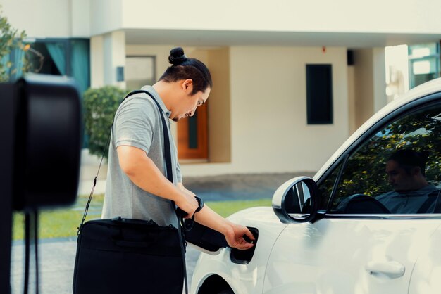 Un homme asiatique progressiste recharge sa voiture EV à la station de charge à domicile