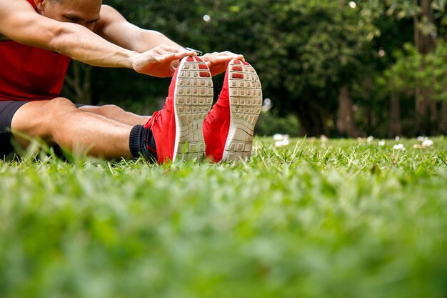 Homme asiatique qui s&#39;étend dans le parc avant de courir le matin