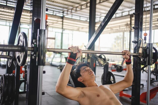 Photo un homme asiatique s'entraîne avec une barre dans le gymnase