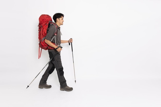 Homme Asiatique Avec Un Sac à Dos Et Des Bâtons De Randonnée Marchant Isolé Sur Fond Blanc