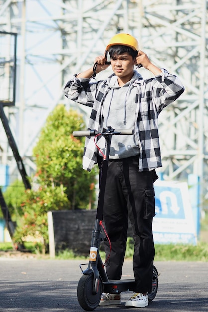 Un homme asiatique se prépare en portant un casque de sécurité avant de conduire un scooter électrique. Moderne et écolo