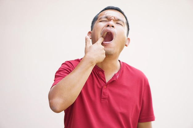 Un homme asiatique souffre de maux de dents à cause des restes de nourriture