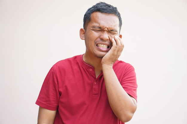 Un homme asiatique souffre de maux de dents à cause des restes de nourriture