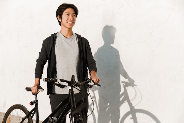 Homme asiatique souriant, faire du vélo à l'extérieur