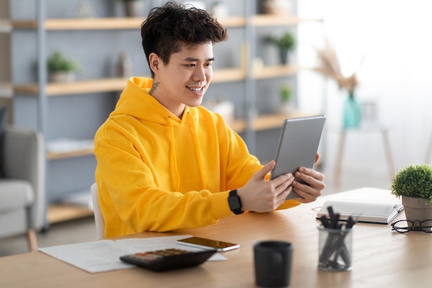 Homme asiatique souriant utilisant une tablette numérique à la maison