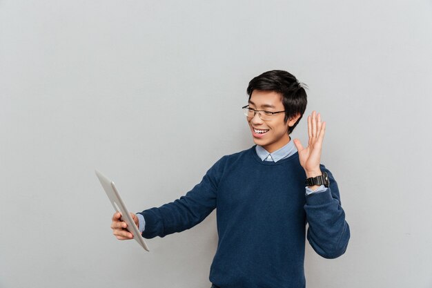 Homme asiatique avec tablette avec lunettes. regarder la tablette