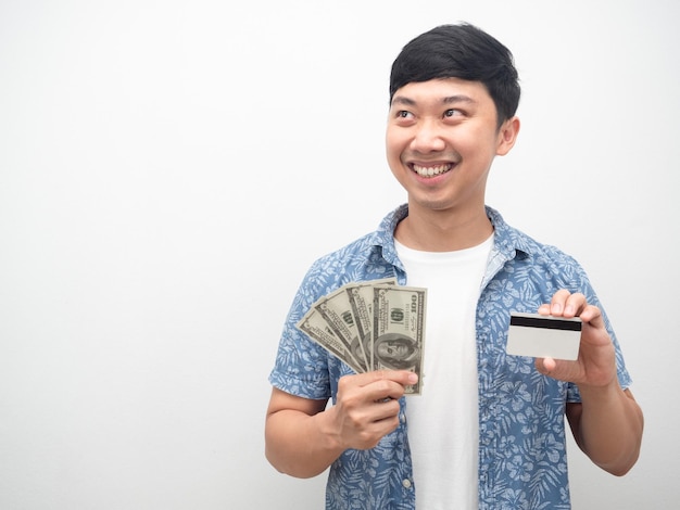 Homme asiatique tenant une carte de crédit et de l'argent sourire heureux en regardant l'espace de copie