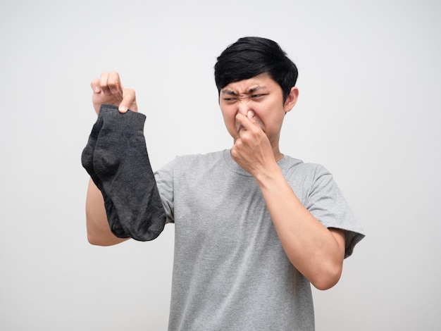 Un homme asiatique tenant des chaussettes sales ferme son nez sent un portrait malodorant
