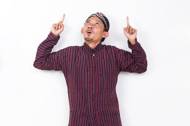 homme asiatique avec un tissu traditionnel javanais lurik pointant les doigts vers différentes directions sur blanc