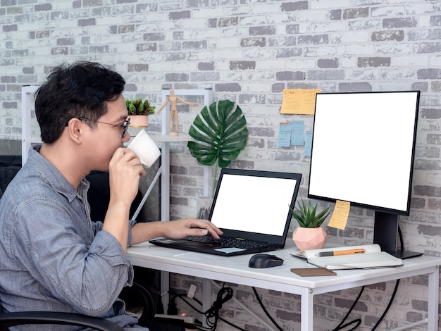 Homme asiatique travaillant avec un ordinateur portable dans sa chambre, copropriété.