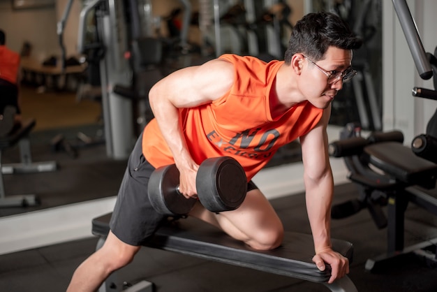 Homme asiatique travaille dans la salle de gym