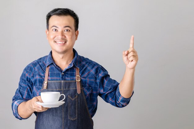 Homme asiatique en uniforme de barista tenant une tasse de café