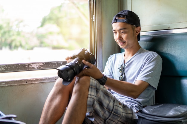 Homme asiatique voyageur avec main tenant l'appareil photo et sac à dos