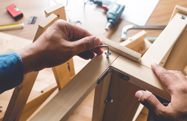 Homme assemblage de meubles en bois, fixation ou réparation de maison avec un tournevis.