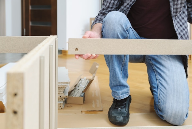 L'homme l'assemblage de meubles à partir de panneaux de particules