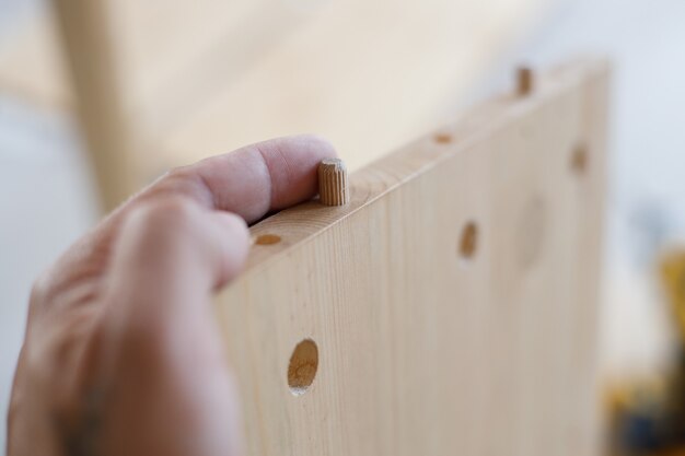 Homme assemblant des meubles en bois à la maison, image en gros plan.